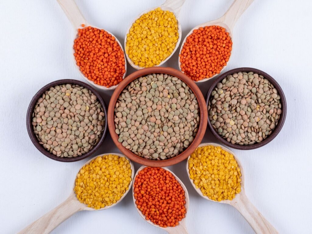 Red, yellow and brown lentils in bowls and spoons