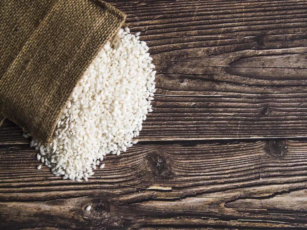 Long grain white rice spilling from a jute sack onto a wooden table